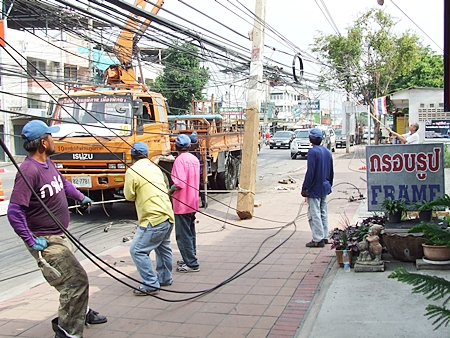 Provincial Electrical Authority workers erect a new utility pole in Naklua, one of a string of 11 leaning and crooked utility poles being replaced between Naklua sois 23 to 29.